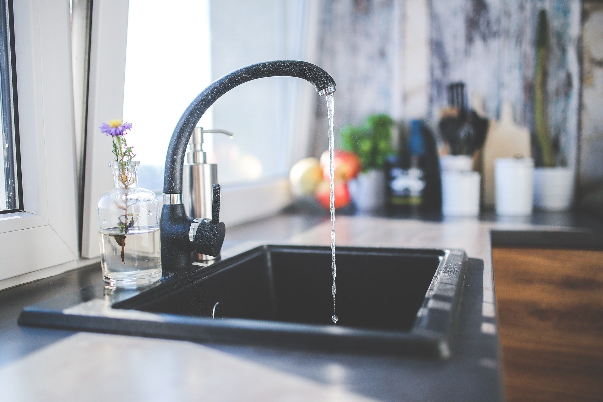 Eau potable gaspillée dans une cuisine par un robinet ouvert.