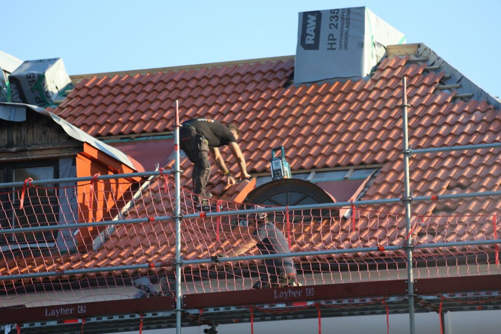 Deux ouvriers sur le chantier de travaux de toitures d'une maison.